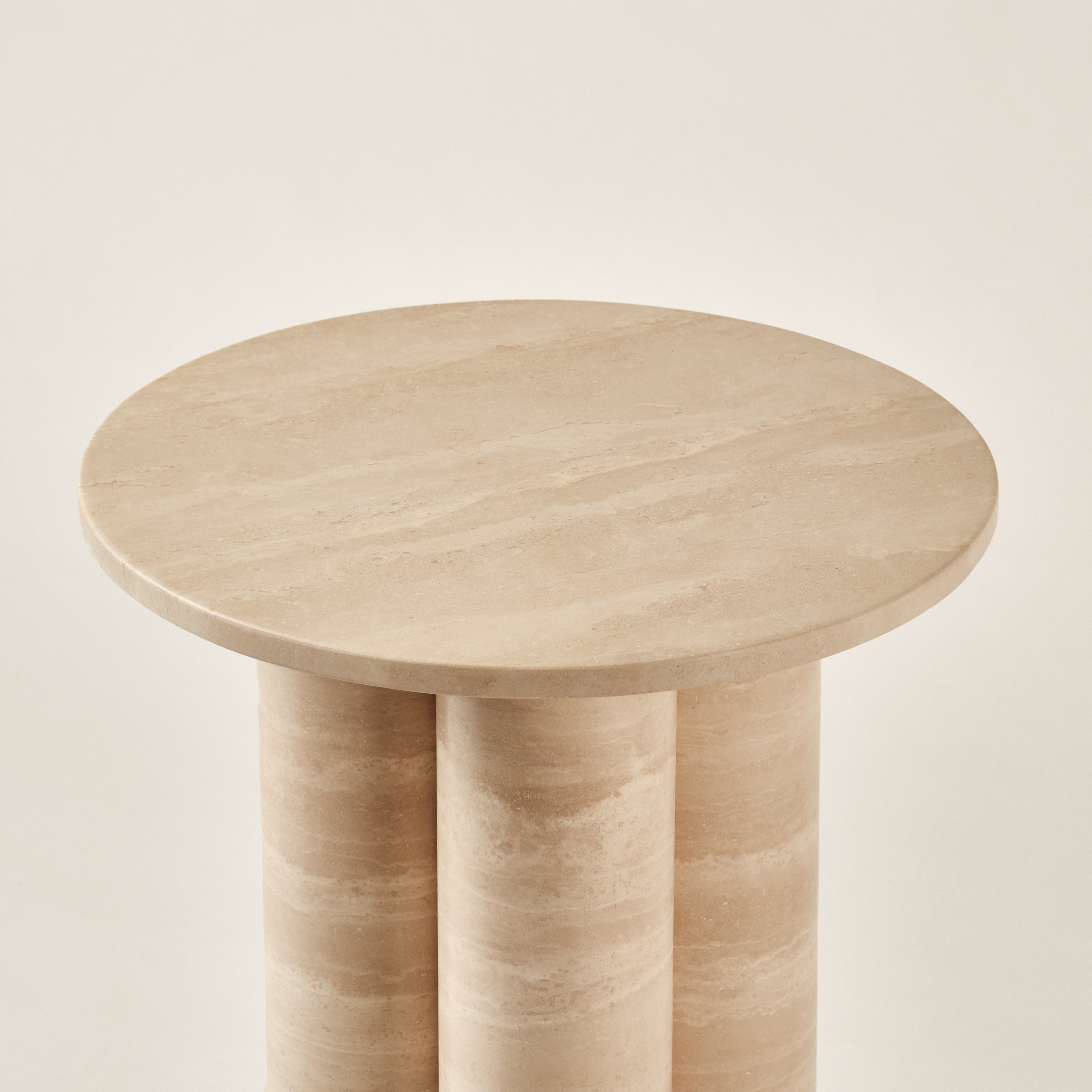 Detailaufnahme eines Beistelltisches aus Travertin mit runder Tischplatte und zylinderförmigen Beinen, die die natürliche Maserung des Steins betonen. Perfekt für stilvolle und minimalistische Innenräume.