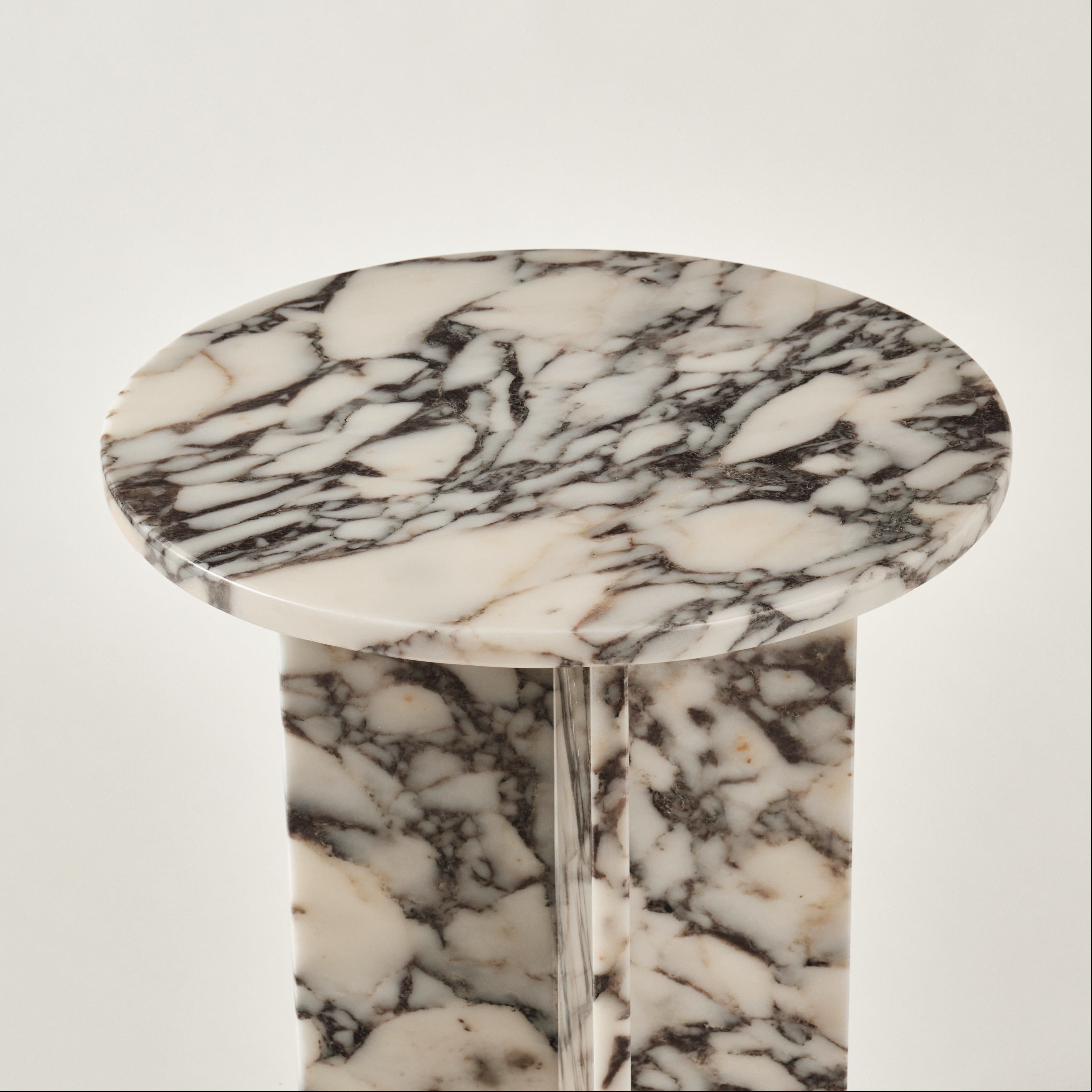 Detailaufnahme eines Beistelltisches aus Marmor mit runder Tischplatte und intensiver Schwarz-Weiß-Maserung, die die natürliche Eleganz und hochwertige Verarbeitung des Materials hervorhebt. Ideal für moderne und luxuriöse Wohnräume.