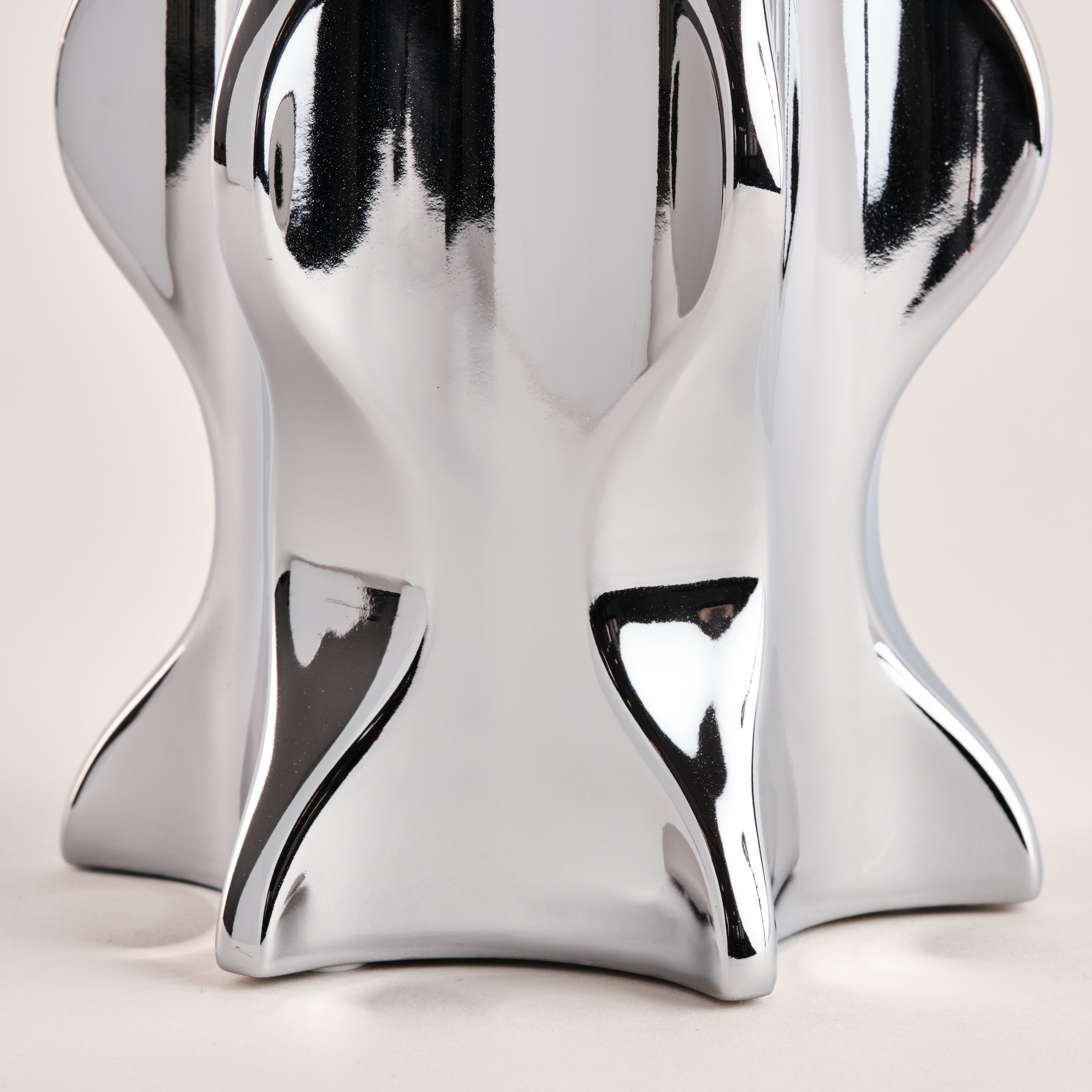 Detailansicht der Basis der Porzellanvase "Cactus" in glänzendem Chrom. Die geschwungenen und organischen Formen des Designs reflektieren das Licht und verleihen der Vase ein elegantes und zeitgemäßes Aussehen.