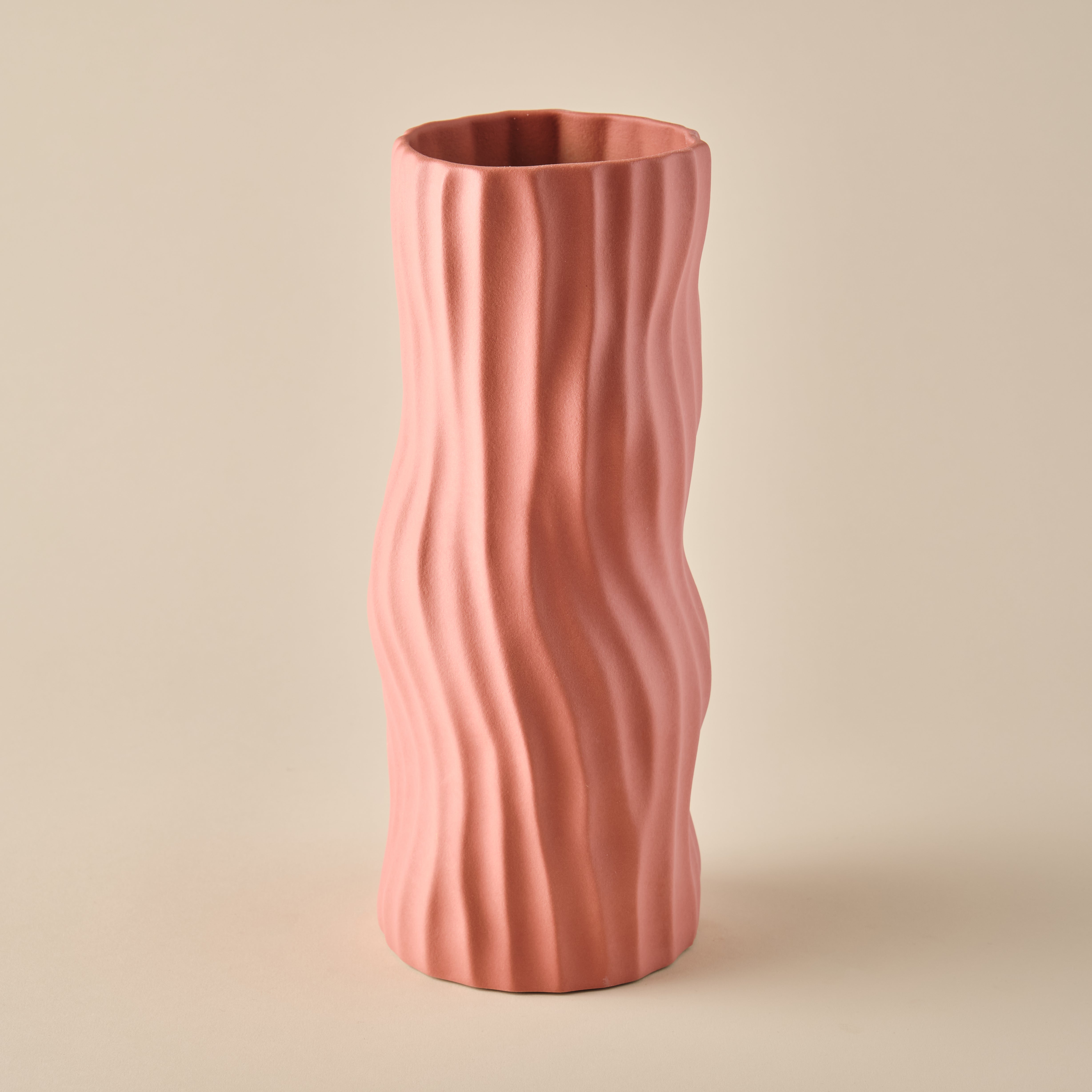 Porzellanvase aus der Kollektion "Coral" in einem eleganten Korallenrosa. Die Vase zeichnet sich durch ihre organische Wellenstruktur und moderne Ästhetik aus. Perfekt als Design-Highlight in zeitgemäßen Wohnräumen.