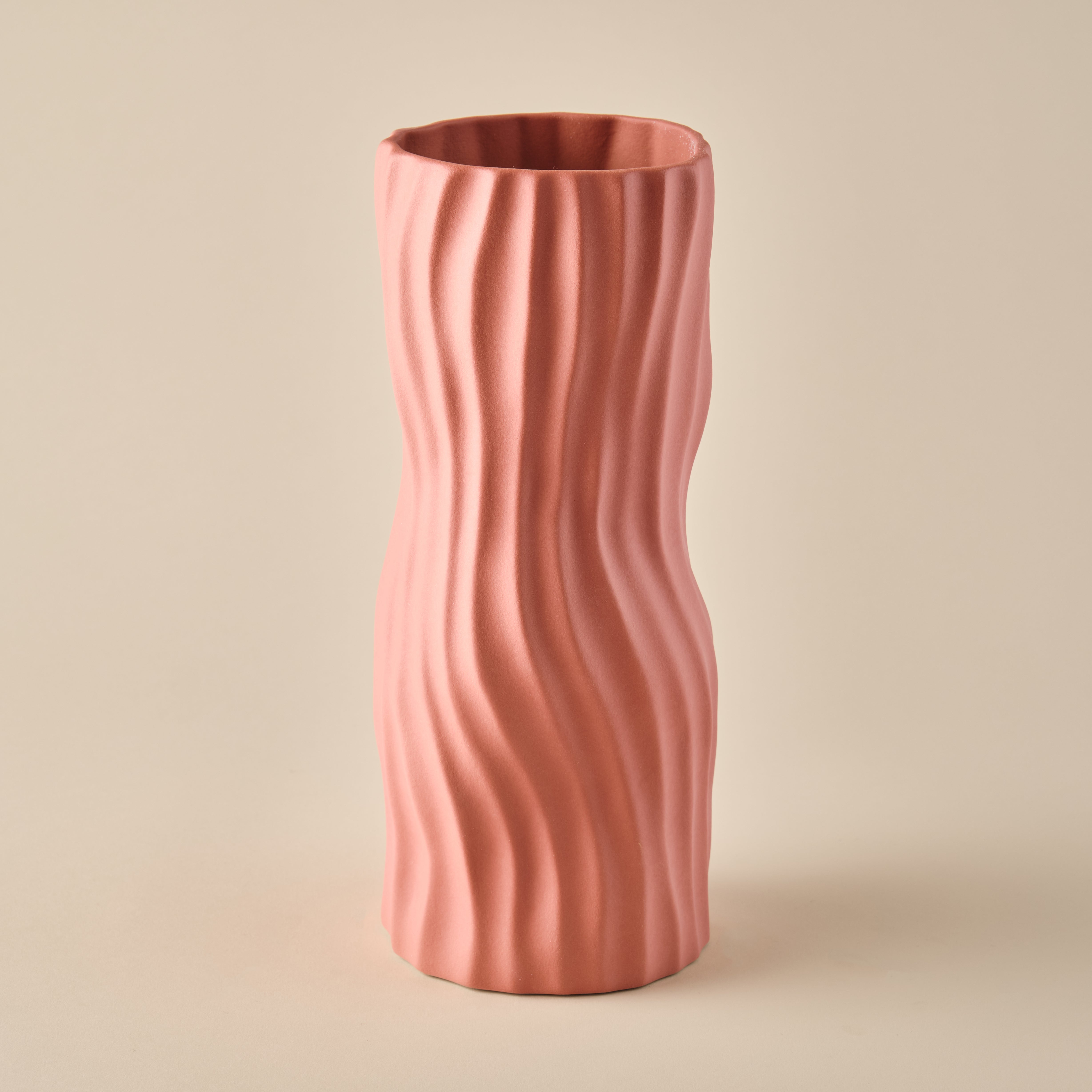 Die Porzellanvase "Coral" in einem warmen Korallenrosa-Ton mit einer wellenförmigen Struktur. Die schlanke, organische Form macht die Vase zu einem stilvollen Akzent für moderne Wohn- und Dekorationsideen. Ideal für Blumenarrangements oder als eigenständiges Kunstobjekt.
