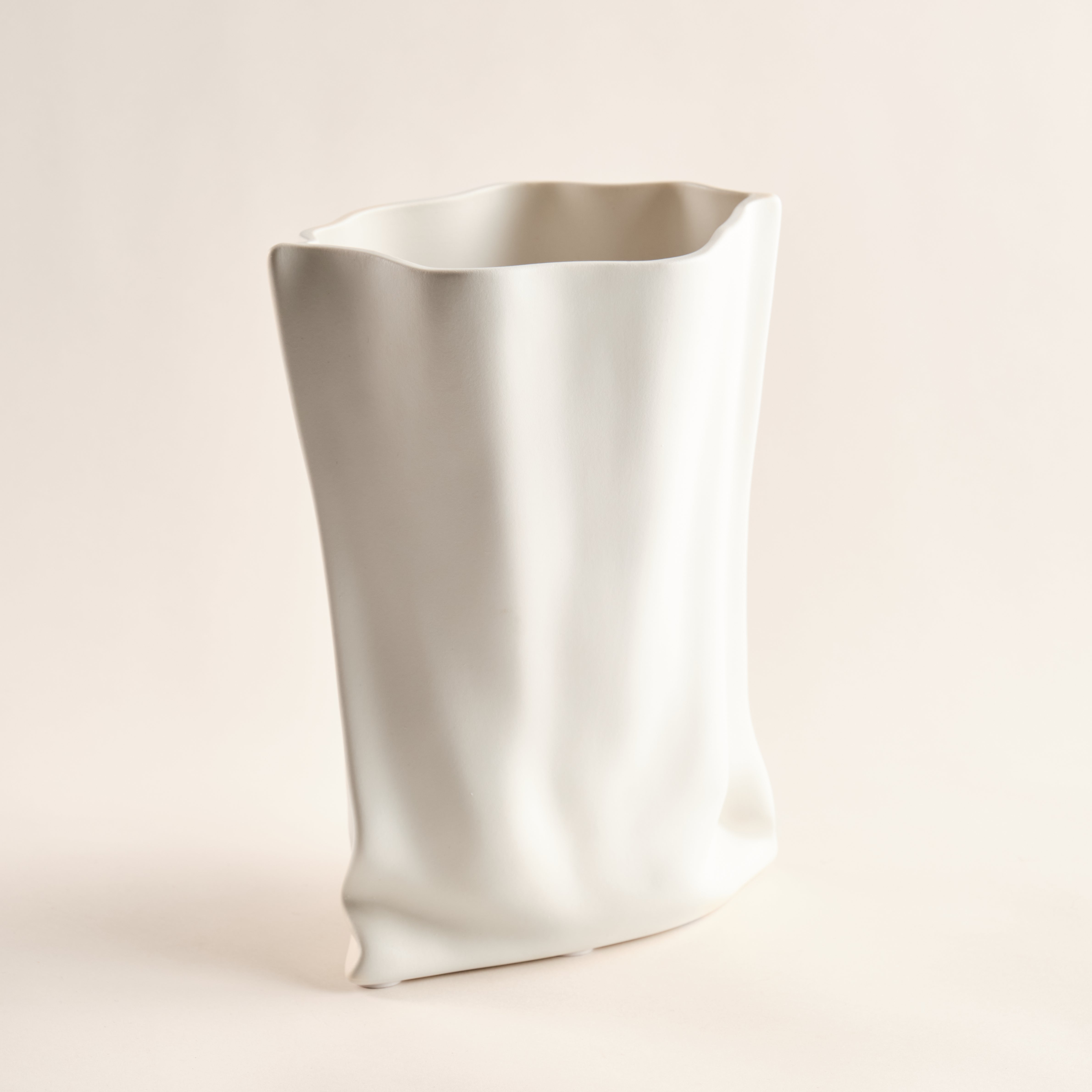 Porzellanvase "Paper Bag" in einzigartigem Design, das an eine sanft zerknitterte Papiertüte erinnert. Perfekt als moderner Blickfang für stilvolle Wohnräume.