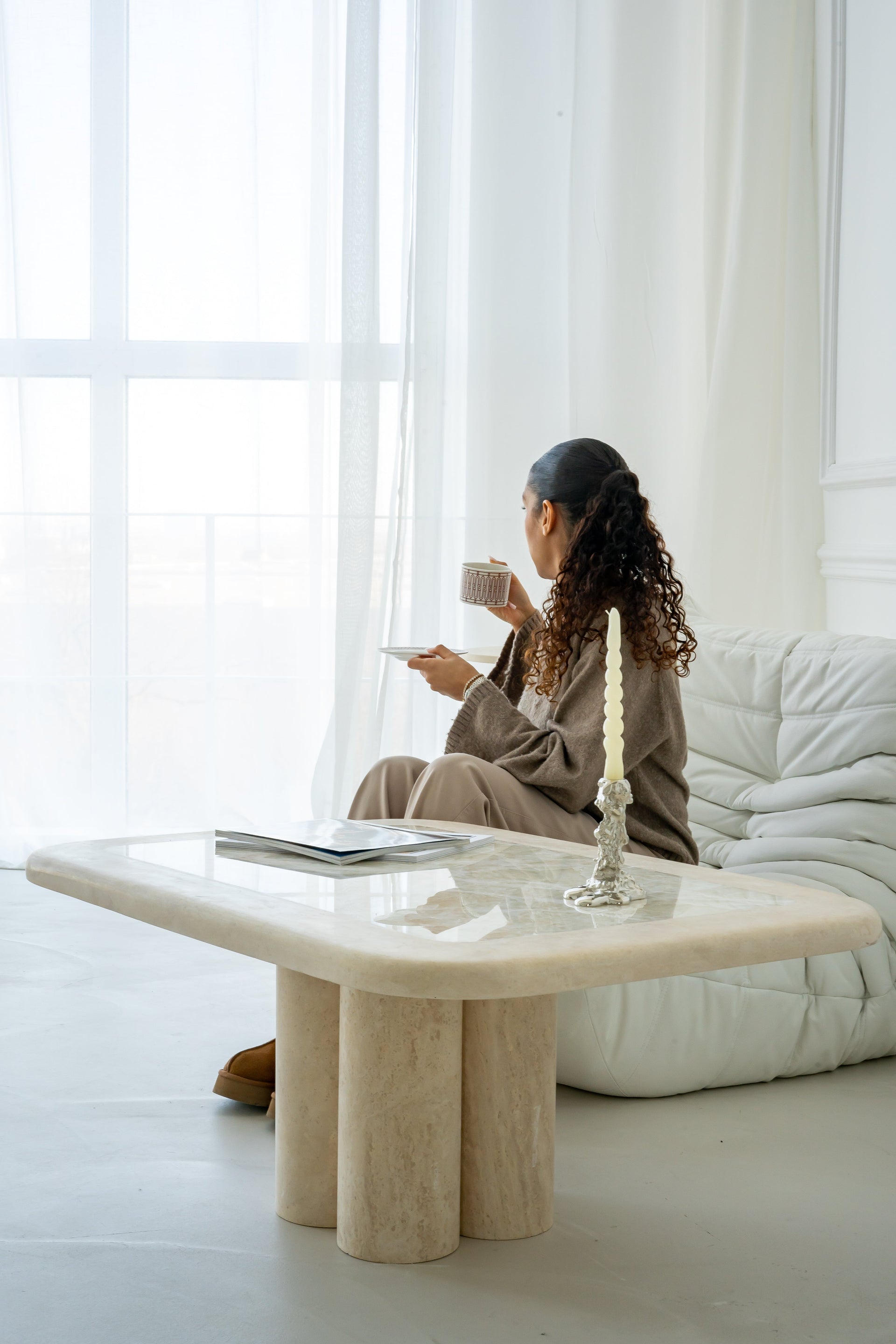 Minimalistischer Couchtisch aus Travertin und Onyx mit abgerundeten Kanten, in einem hellen, modernen Wohnzimmer. Stilvolle Einrichtung mit eleganter Atmosphäre, ideal für zeitgenössisches Design