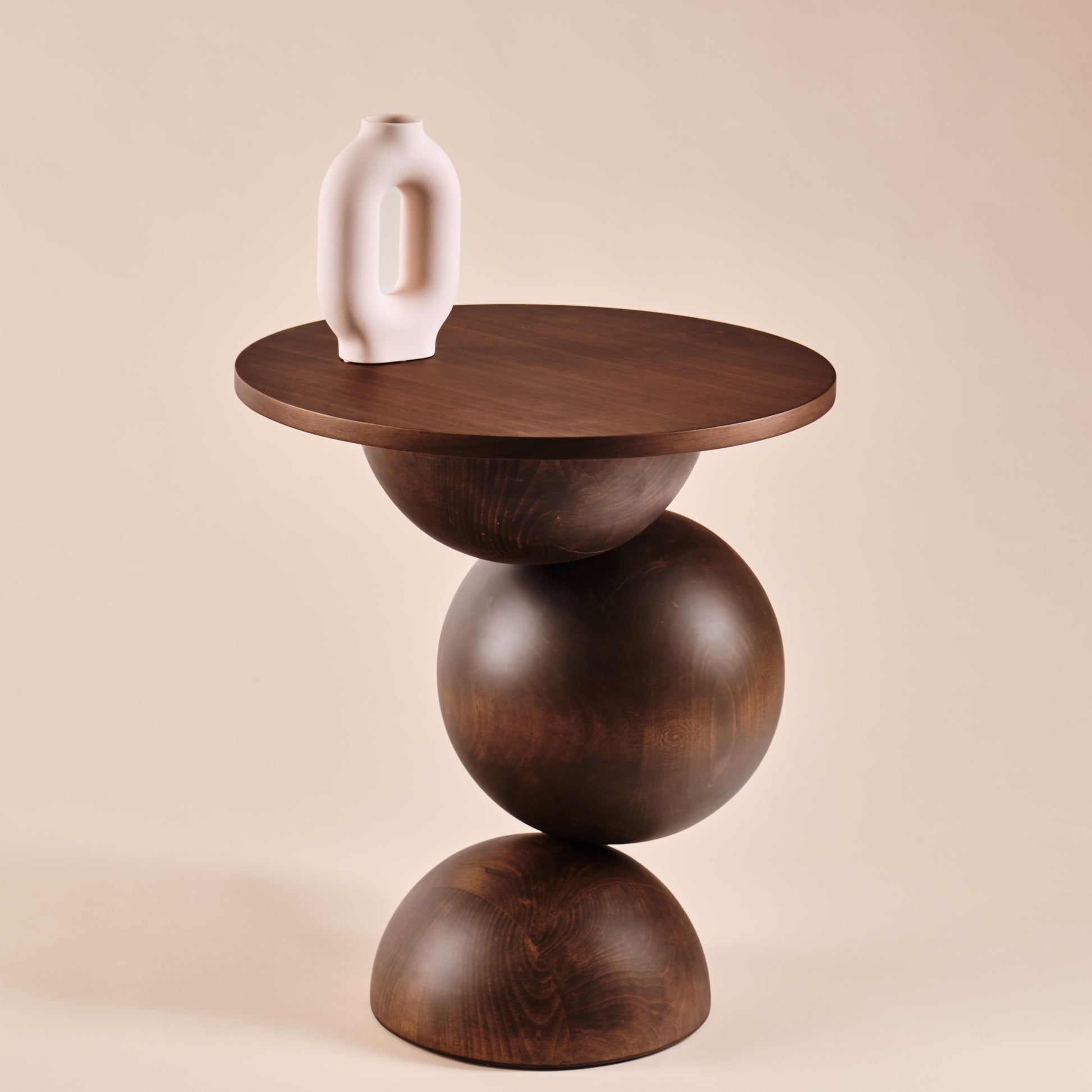 Beistelltisch Universe aus Holz mit runder Tischplatte und skulpturalem Design, dekoriert mit einer modernen weißen Keramikvase. Perfekt für stilvolle Wohnräume und zeitgemäße Einrichtung.