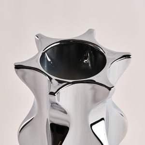 Nahaufnahme der Porzellanvase "Cactus" in glänzendem Chrom. Die auffällige, sternförmige Öffnung und die geschwungenen Kanten der Vase unterstreichen das elegante und moderne Design.