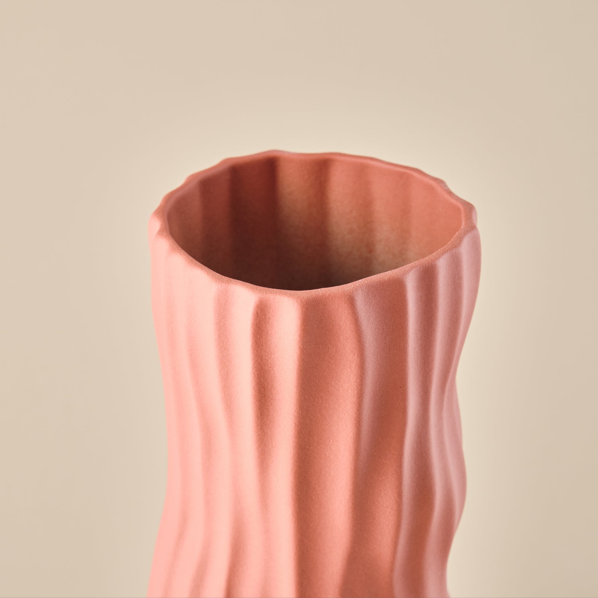 Nahaufnahme der Porzellanvase "Coral" in korallenrosa. Deutlich sichtbar ist die elegante, wellenförmige Struktur, die dieser Vase eine moderne und organische Ästhetik verleiht. Perfekt als stilvolles Deko-Element.