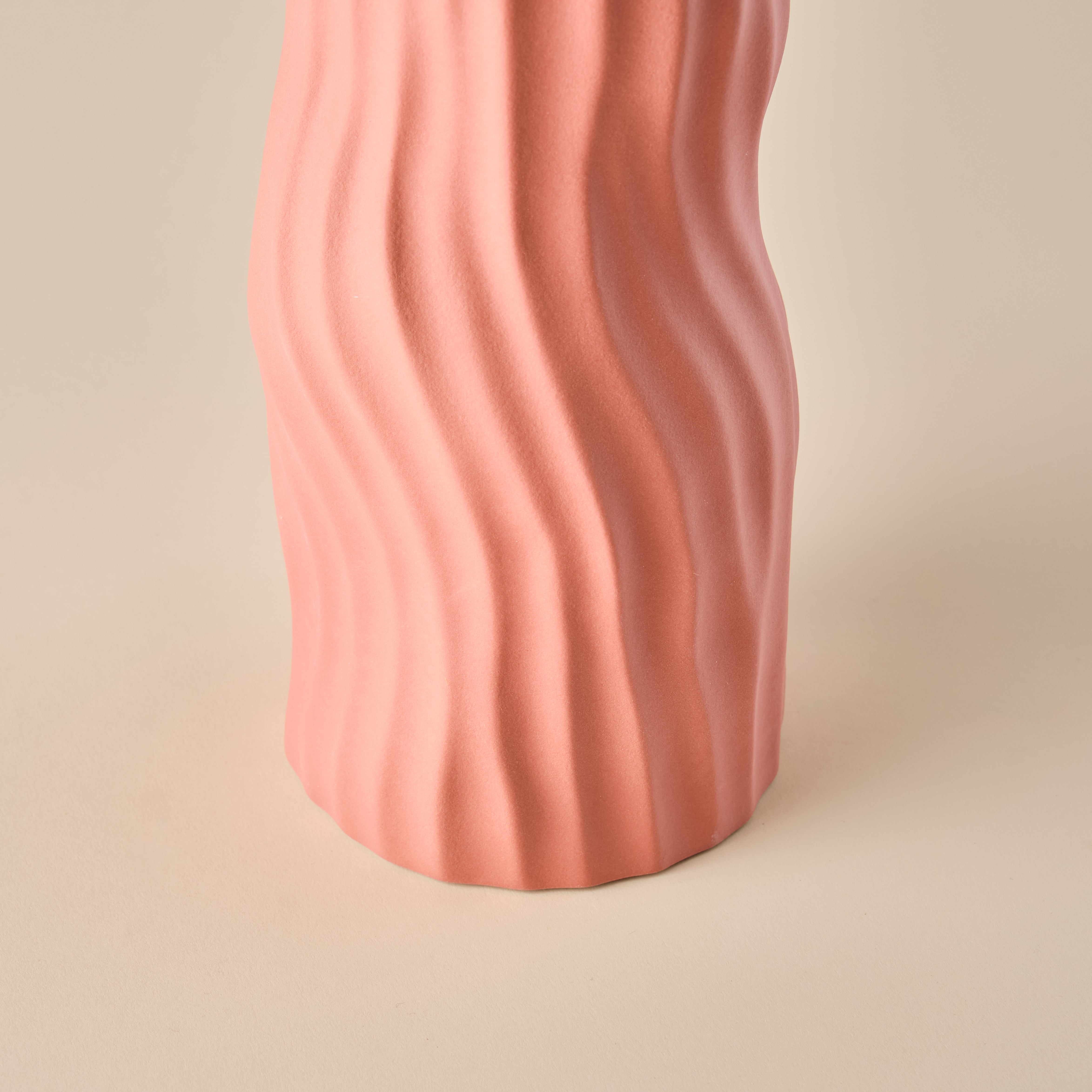 Nahaufnahme der Porzellanvase "Coral" in einem warmen korallenrosa Farbton. Die wellenförmige Struktur verleiht der Vase eine organische und zeitlose Ästhetik. Perfekt als dekoratives Highlight in modernen Wohnräumen.