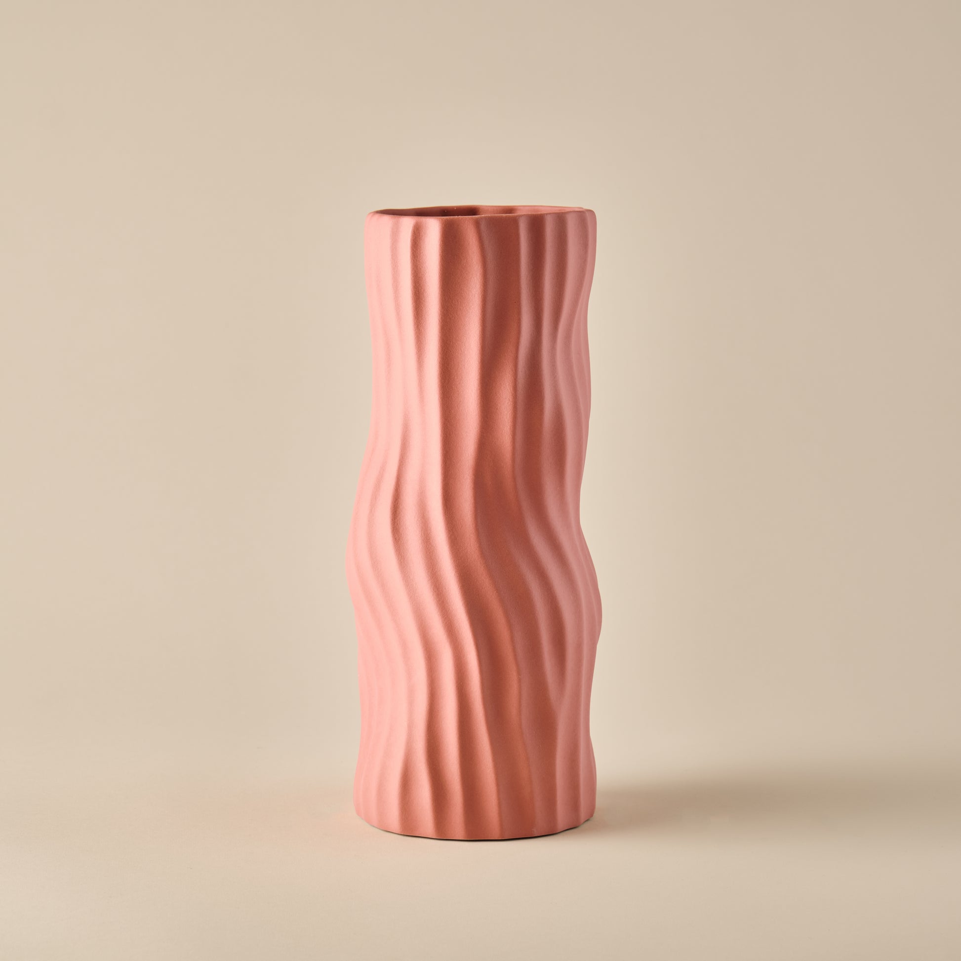 Porzellanvase "Coral" in einem sanften korallenrosa Farbton. Die Vase zeichnet sich durch ihre schlanke Form und die organischen Wellenlinien aus, die einen modernen und natürlichen Look erzeugen. Perfekt für zeitgemäße Wohnräume und dekorative Akzente.