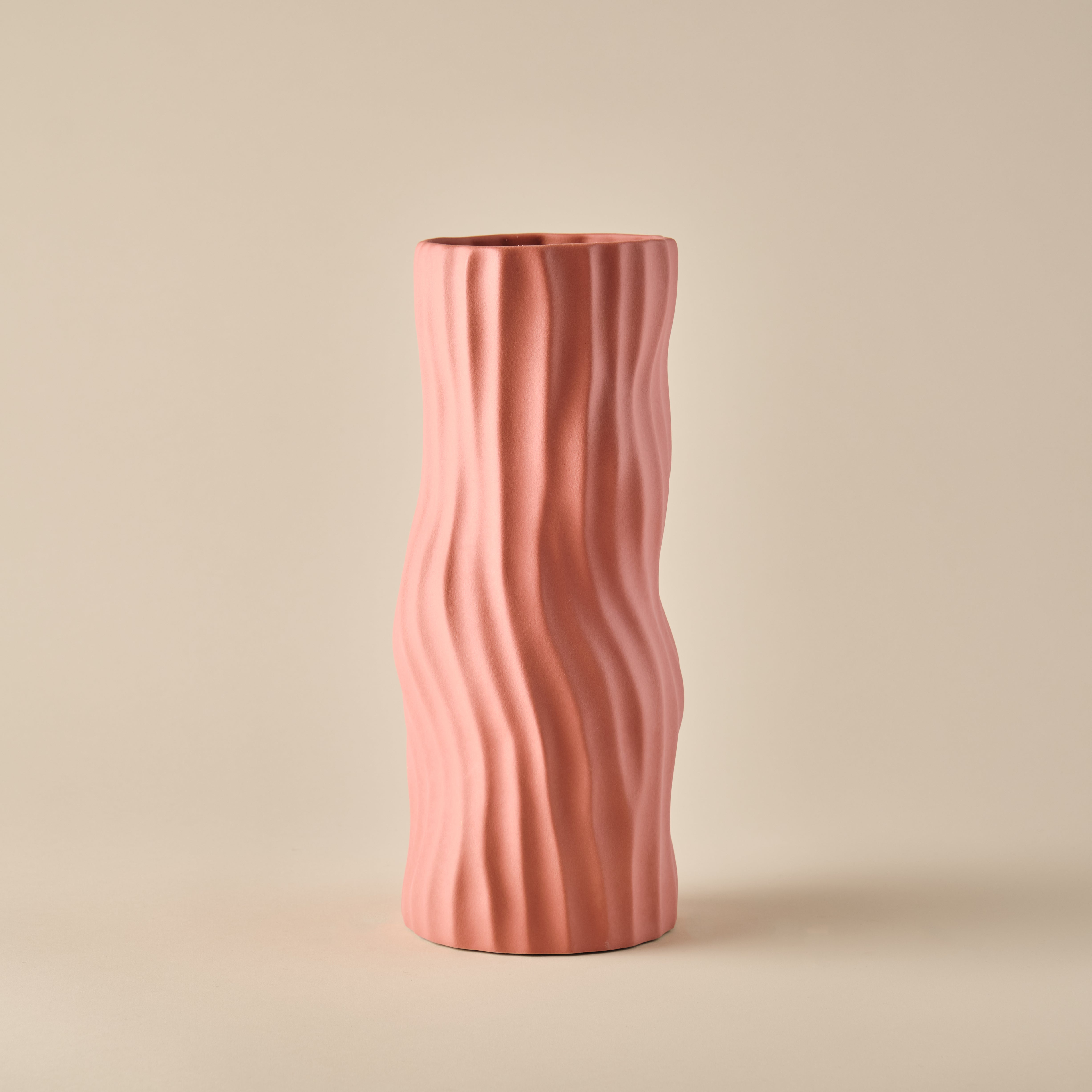 Porzellanvase "Coral" in einem sanften korallenrosa Farbton. Die Vase zeichnet sich durch ihre schlanke Form und die organischen Wellenlinien aus, die einen modernen und natürlichen Look erzeugen. Perfekt für zeitgemäße Wohnräume und dekorative Akzente.