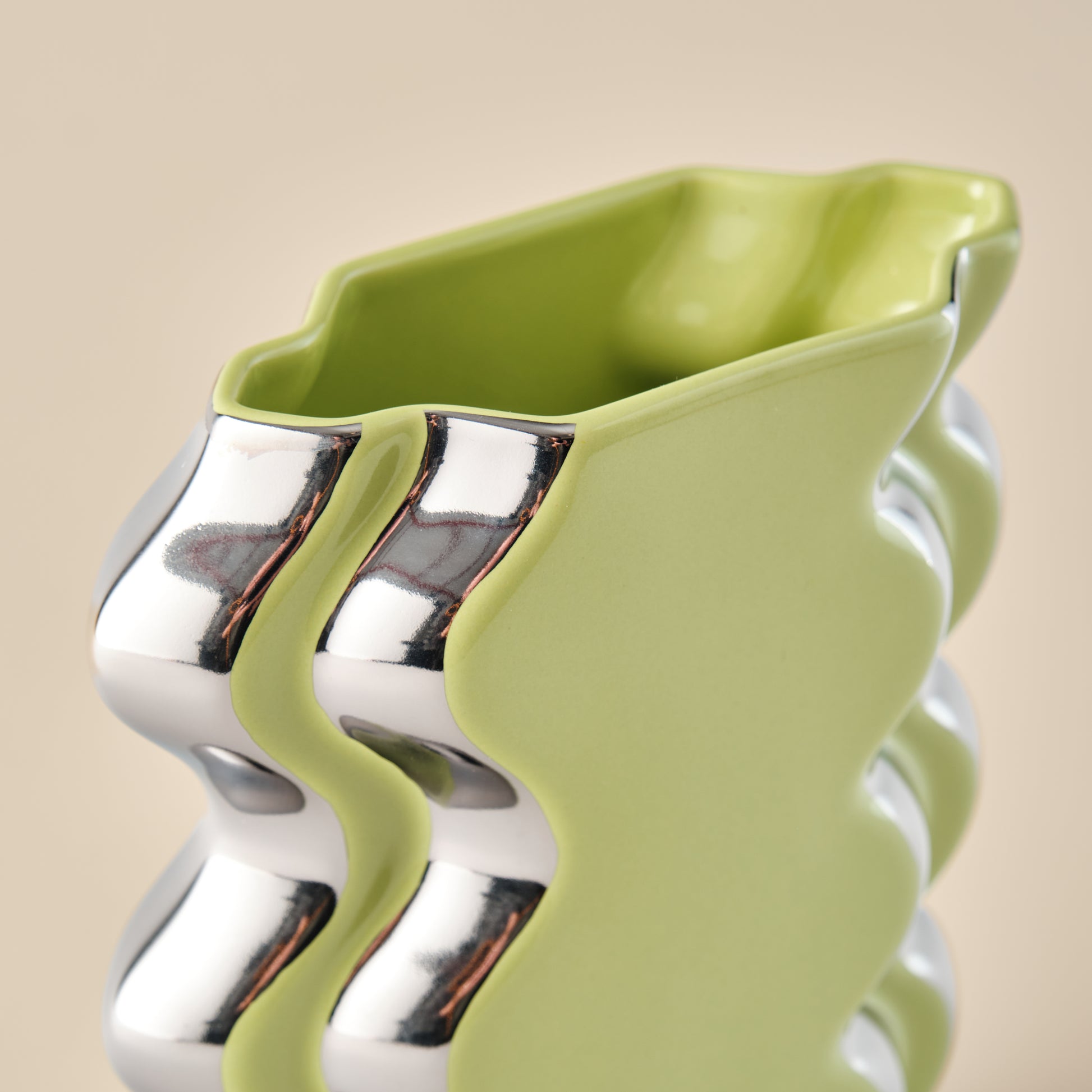 Nahaufnahme der Porzellanvase "Double Curl" in leuchtendem Limettengrün mit eleganten Chromdetails und wellenförmigem Design. Ein moderner Blickfang für jedes Zuhause.