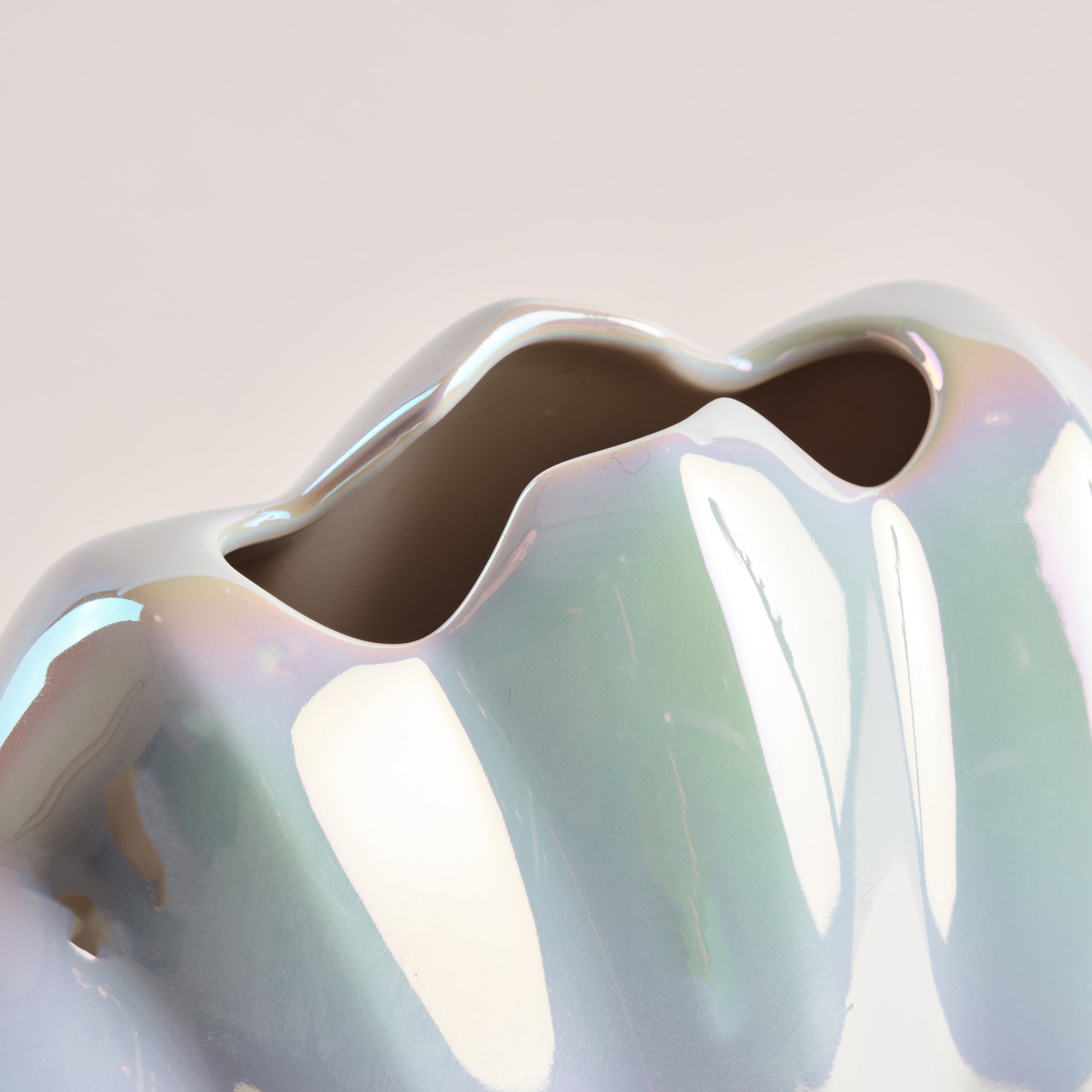 Nahaufnahme der Porzellanvase "Seashell Rainbow" mit schimmernder Regenbogen-Glasur und geschwungenem Öffnungsdesign, das die Eleganz und Qualität der Muscheloptik hervorhebt.
