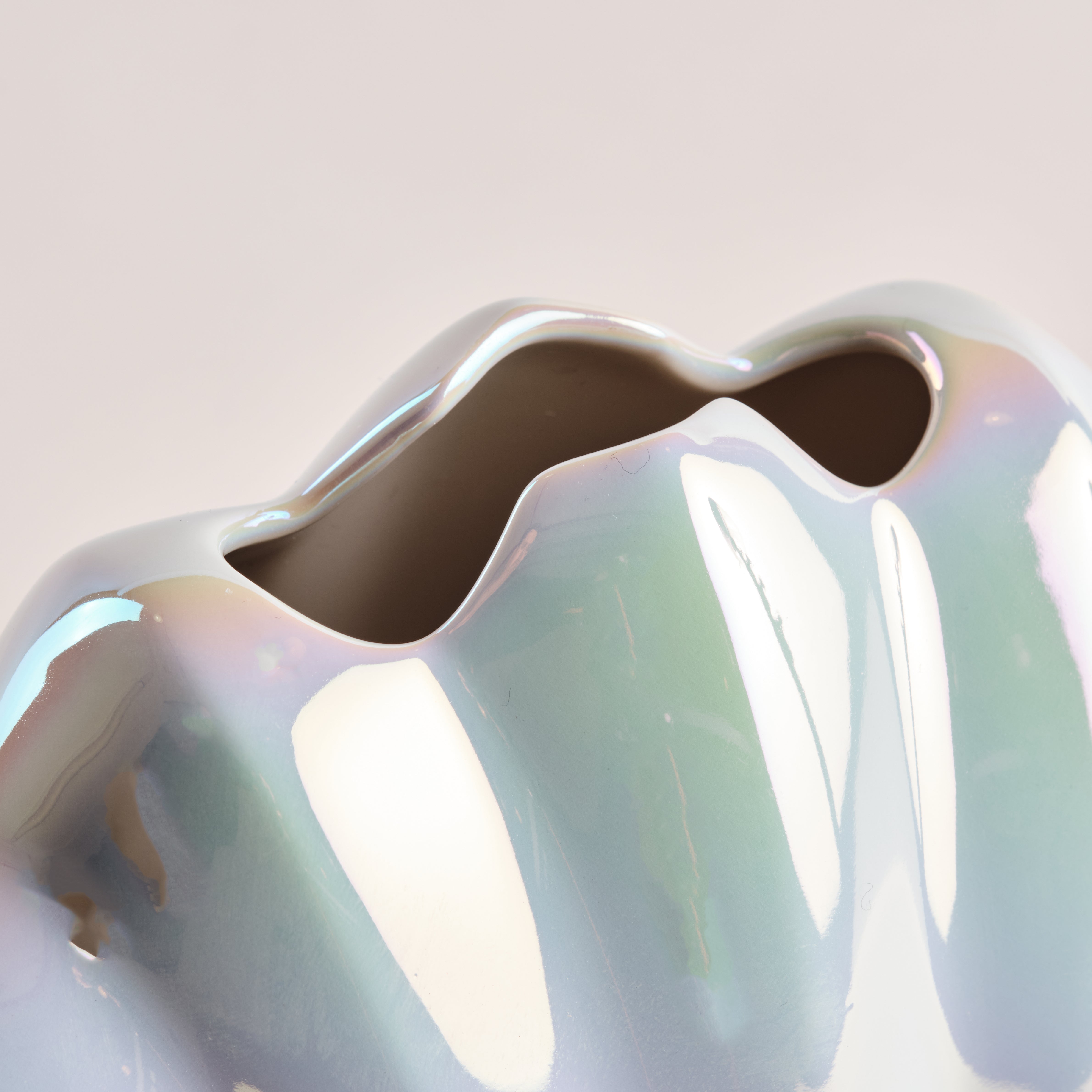 Nahaufnahme der Porzellanvase "Seashell Rainbow" mit schimmernder Regenbogen-Glasur und geschwungenem Öffnungsdesign, das die Eleganz und Qualität der Muscheloptik hervorhebt.