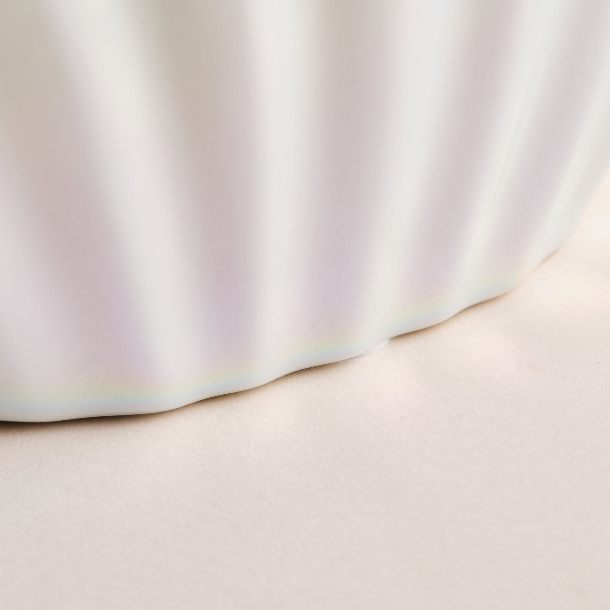 Nahaufnahme der Porzellanvase "Seashell Rainbow", die die feine, wellenförmige Struktur und die glänzende Regenbogenglasur im unteren Bereich der Vase hervorhebt. Ein elegantes Detail aus der exklusiven Porzellankollektion.