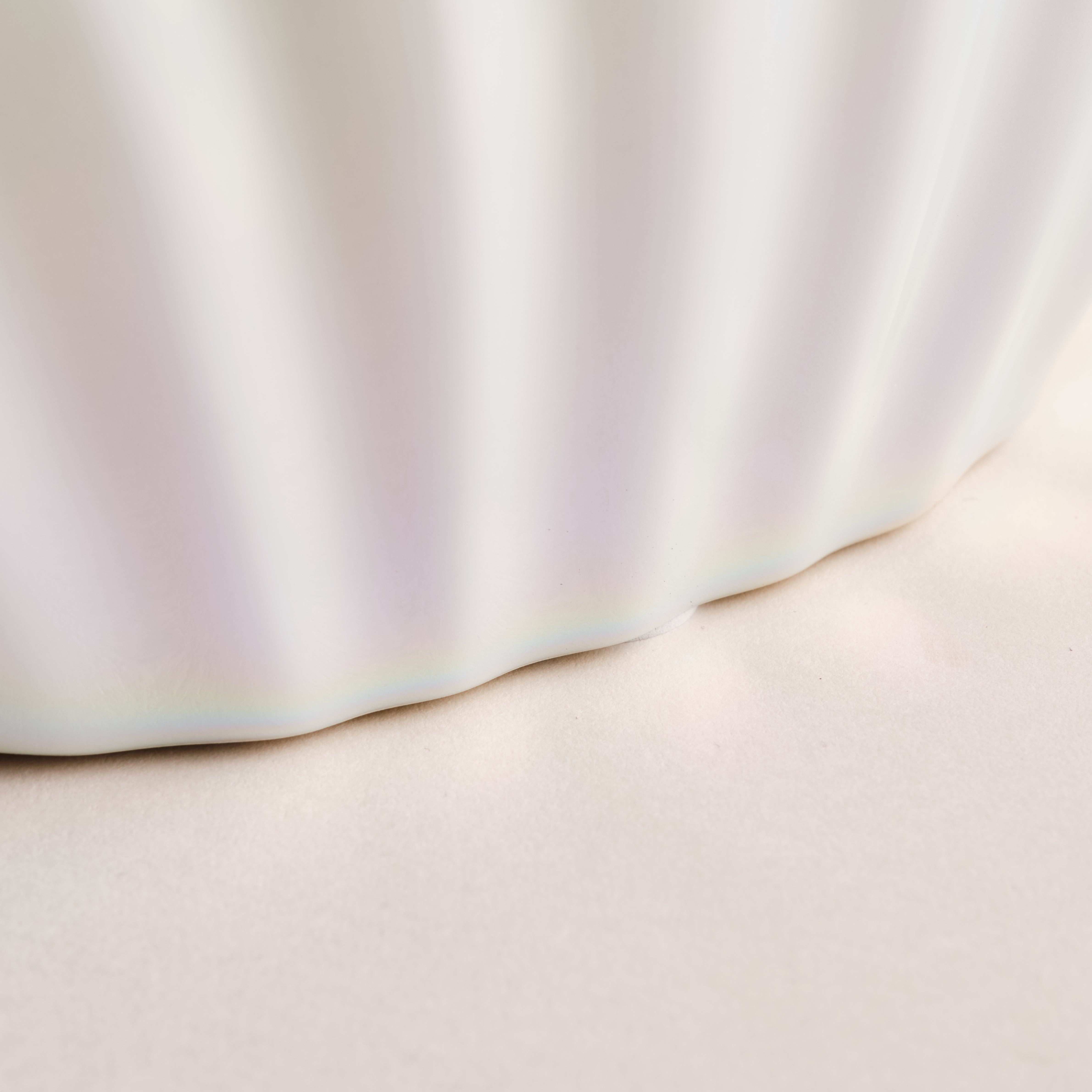 Nahaufnahme der Porzellanvase "Seashell Rainbow", die die feine, wellenförmige Struktur und die glänzende Regenbogenglasur im unteren Bereich der Vase hervorhebt. Ein elegantes Detail aus der exklusiven Porzellankollektion.