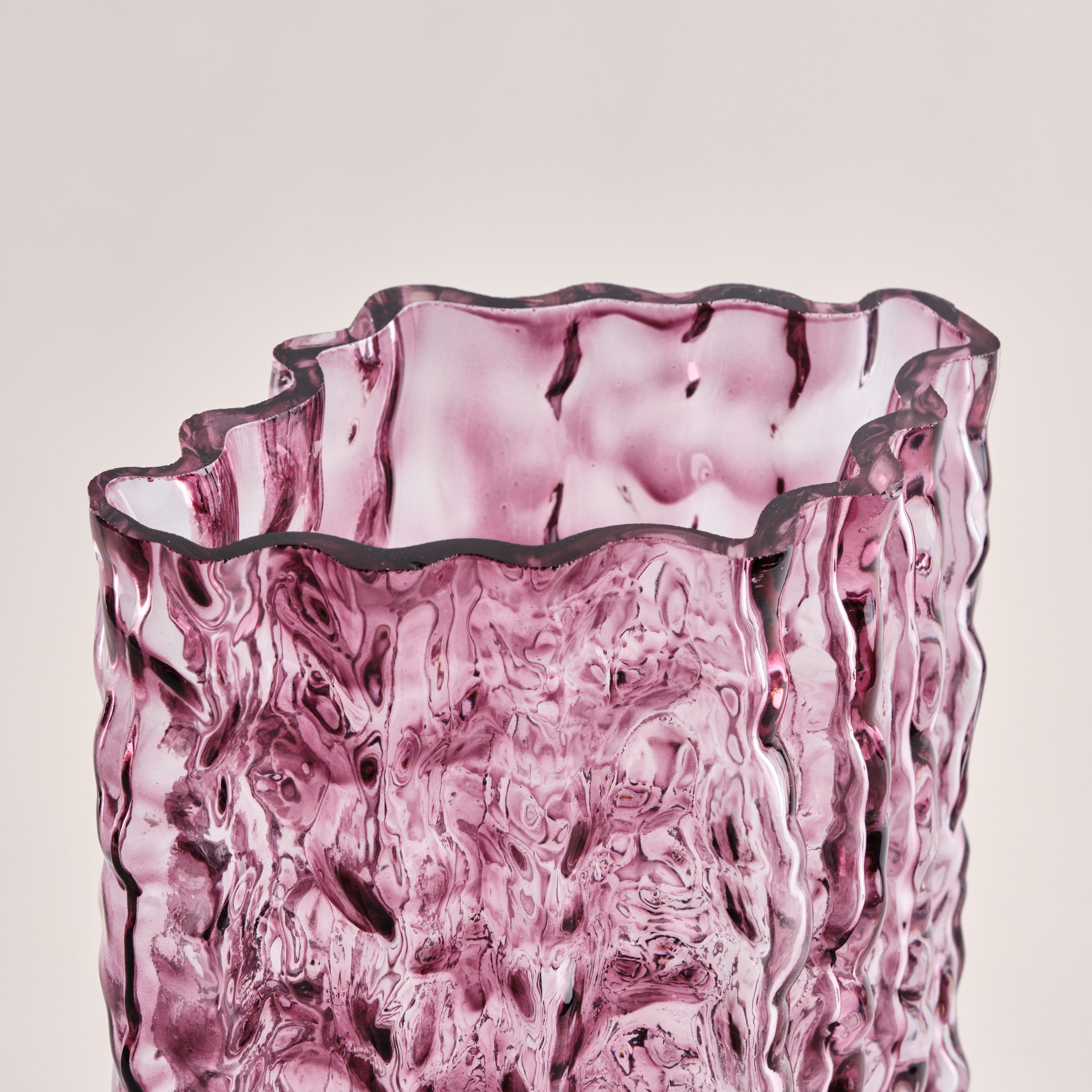 Nahaufnahme der Glasvase Raw in Rosa. Die wellenförmige, strukturierte Oberfläche reflektiert das Licht und betont das kunstvolle, handgefertigte Design der Vase.