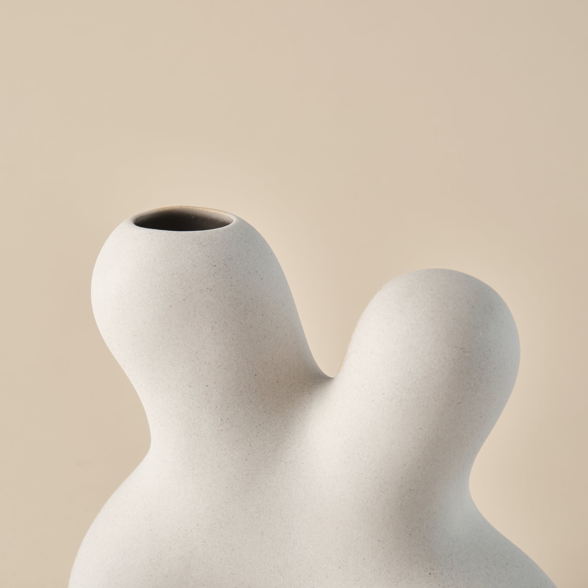 Nahaufnahme der Porzellanvase "Splash" mit geschwungener, organischer Form und glatter, beiger Oberfläche. Perfekt als stilvolle Dekoration in minimalistischen Wohnräumen.