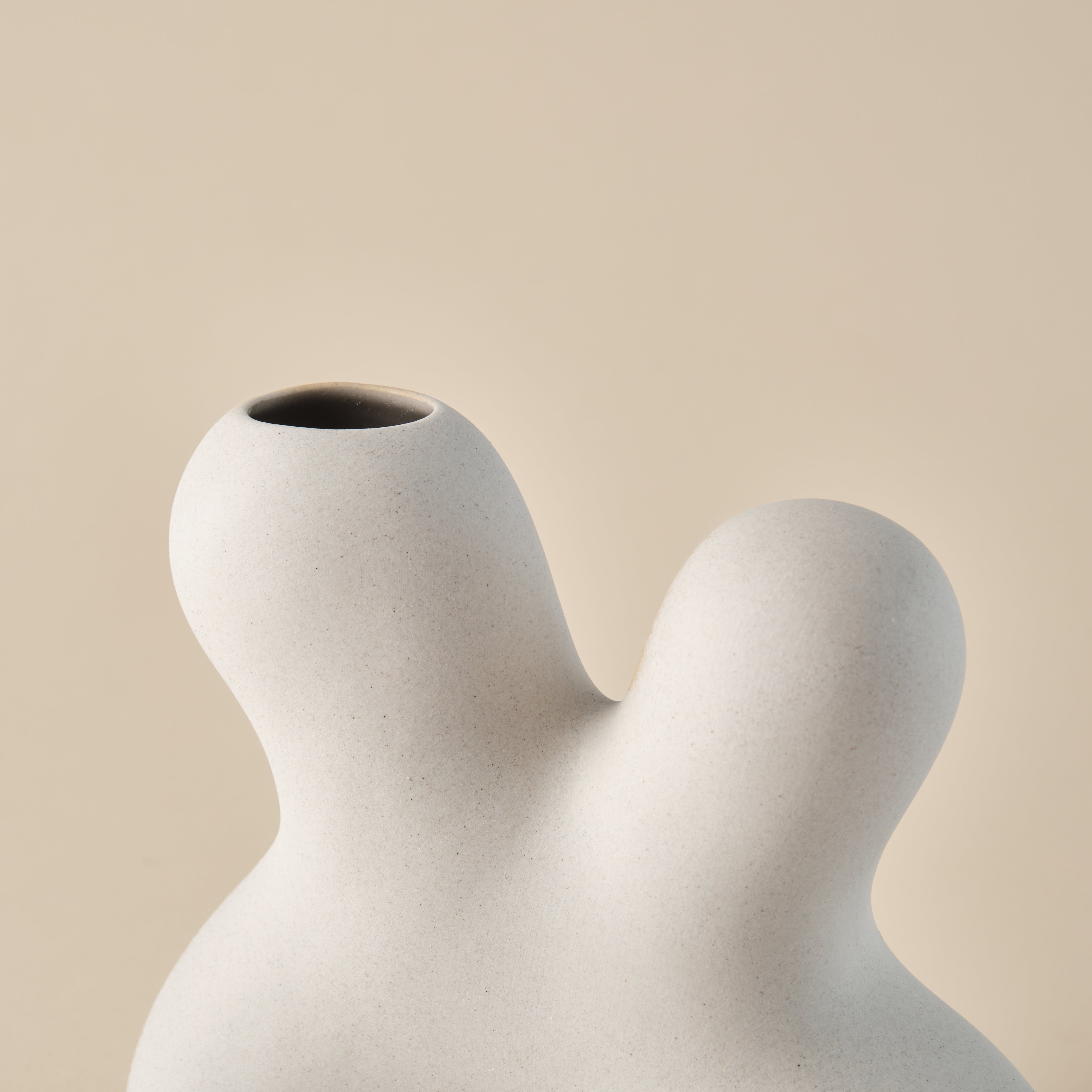 Nahaufnahme der Porzellanvase "Splash" mit geschwungener, organischer Form und glatter, beiger Oberfläche. Perfekt als stilvolle Dekoration in minimalistischen Wohnräumen.