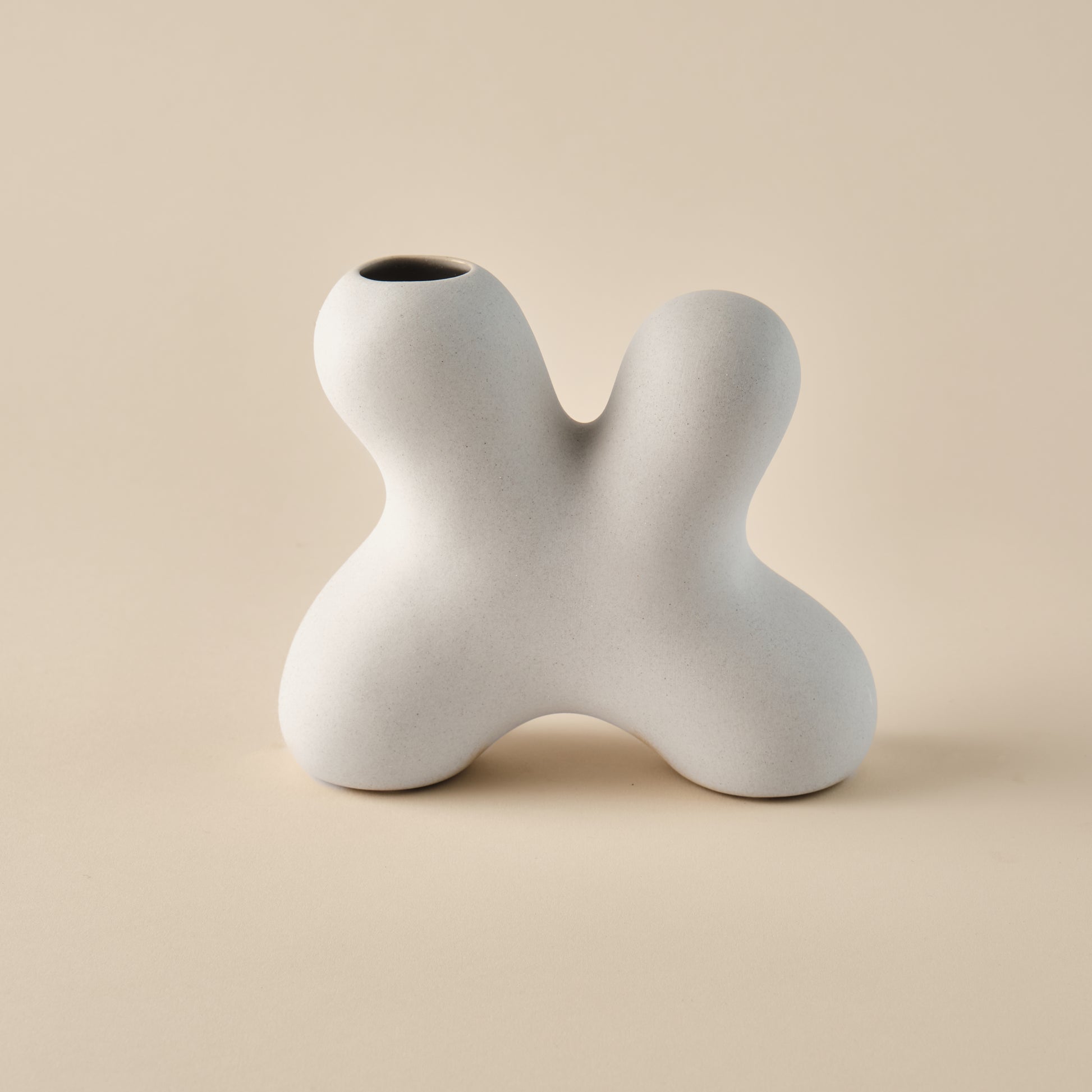 Porzellanvase "Splash" in skulpturaler Form mit geschwungenem, organischem Design. Die minimalistische beige Oberfläche betont die einzigartige Form, ideal für modernes Wohndesign oder als dekoratives Highlight.