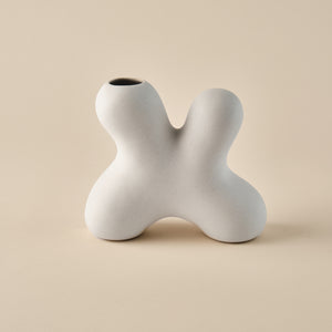 Porzellanvase "Splash" in skulpturaler Form mit geschwungenem, organischem Design. Die minimalistische beige Oberfläche betont die einzigartige Form, ideal für modernes Wohndesign oder als dekoratives Highlight.