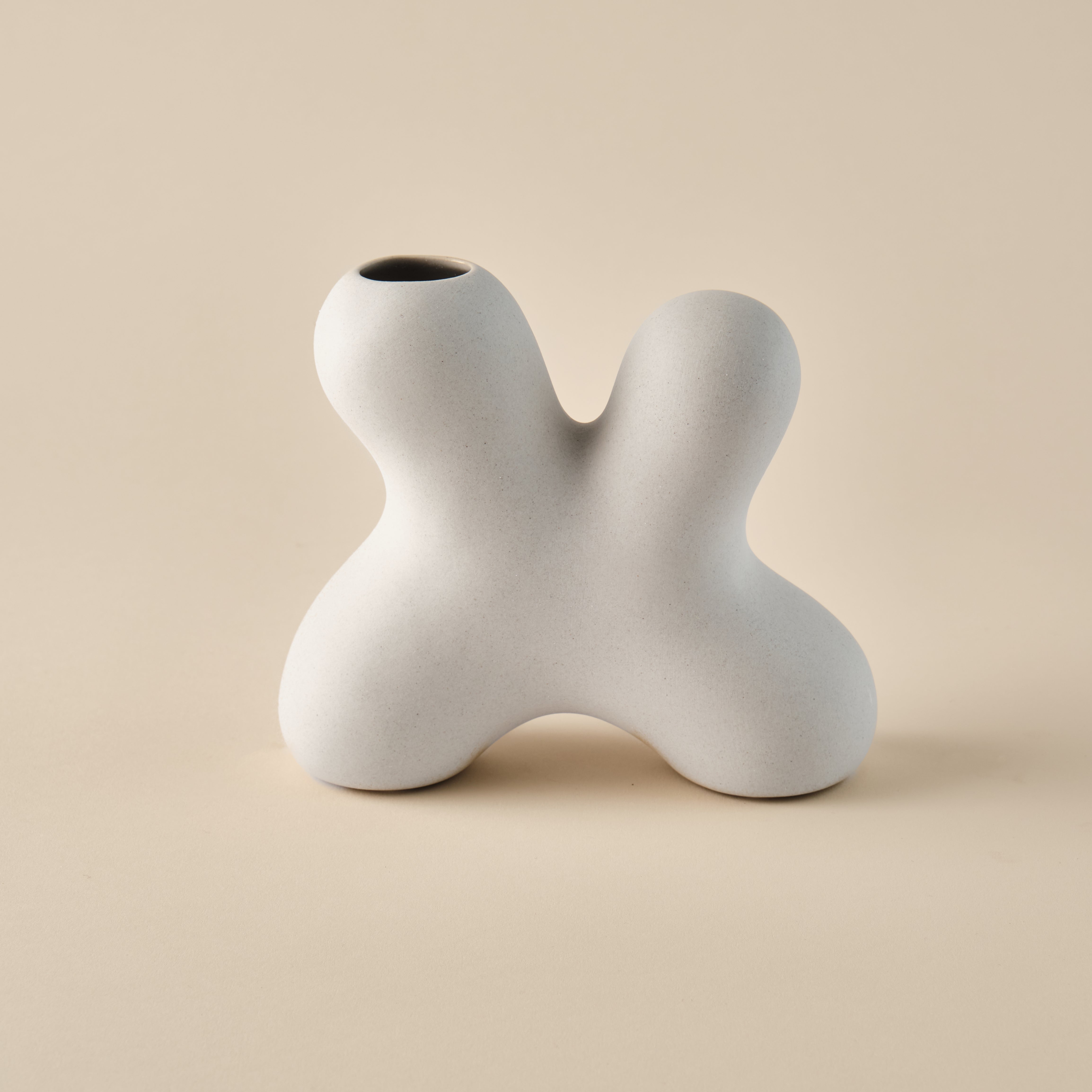 Porzellanvase "Splash" in skulpturaler Form mit geschwungenem, organischem Design. Die minimalistische beige Oberfläche betont die einzigartige Form, ideal für modernes Wohndesign oder als dekoratives Highlight.
