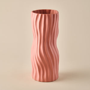 Die Porzellanvase "Coral" in einem warmen Korallenrosa-Ton mit einer wellenförmigen Struktur. Die schlanke, organische Form macht die Vase zu einem stilvollen Akzent für moderne Wohn- und Dekorationsideen. Ideal für Blumenarrangements oder als eigenständiges Kunstobjekt.
