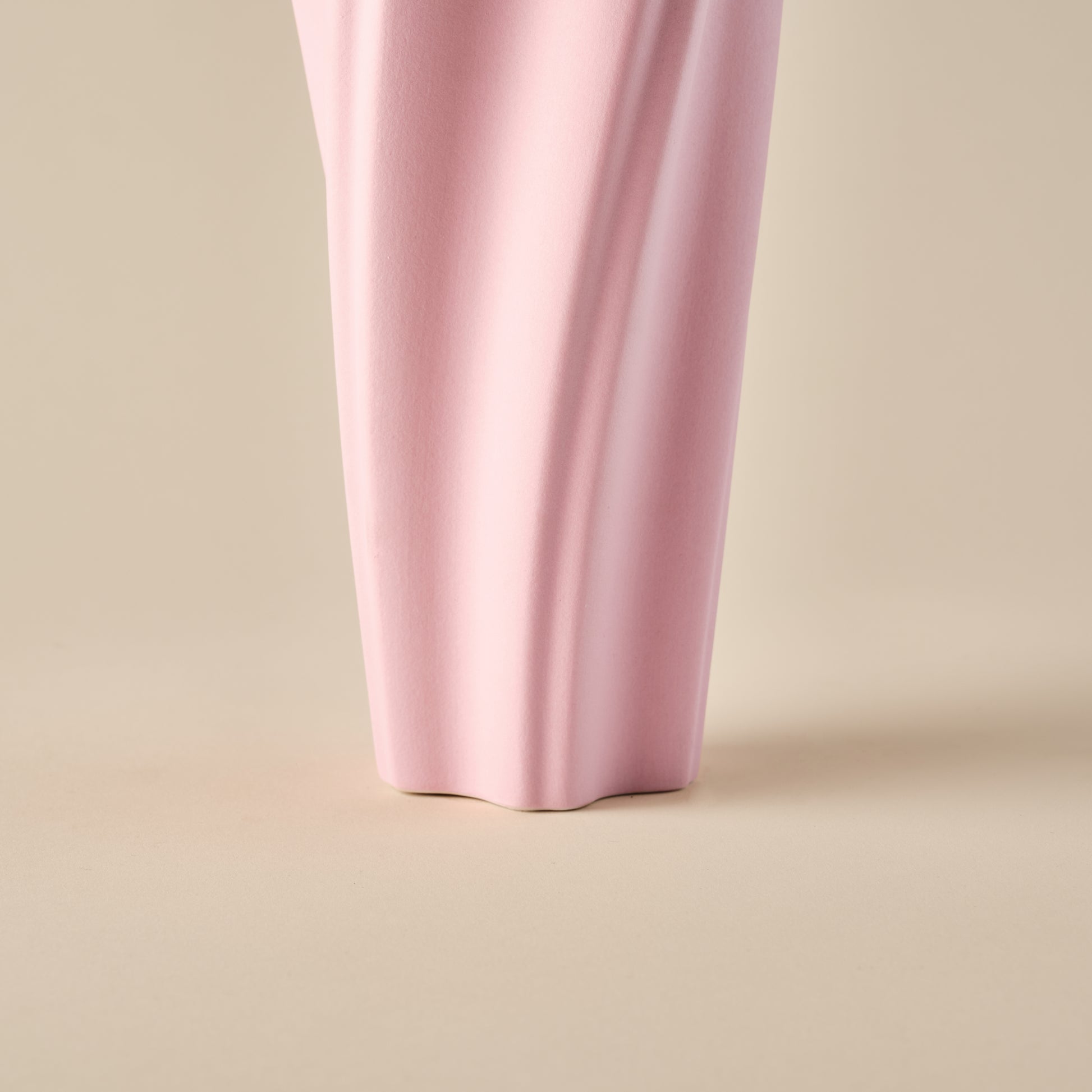 Detailaufnahme der unteren Partie der Porzellanvase "Wind" in Rosa. Die wellenförmige Struktur und der solide Standfuß verleihen der Vase ein elegantes und modernes Design. Ideal für zeitgemäße Wohnraumdekorationen.