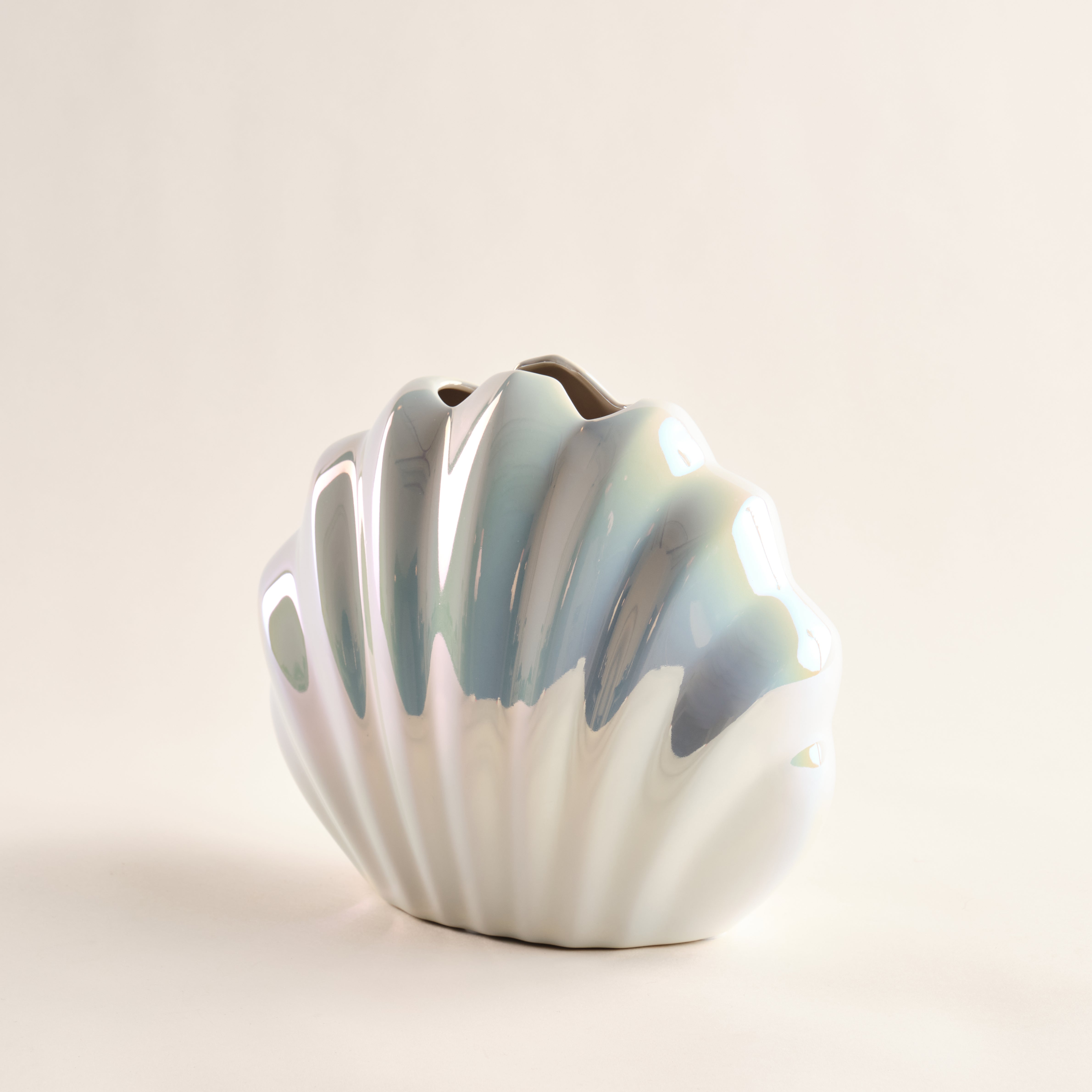 Porzellanvase "Seashell Rainbow" im Muscheldesign mit glänzender Regenbogenglasur. Die Vase zeigt ein wellenförmiges Muster und eine schimmernde Oberfläche, die an einen Meeresschatz erinnert. Ideal für stilvolle Raumdekoration.