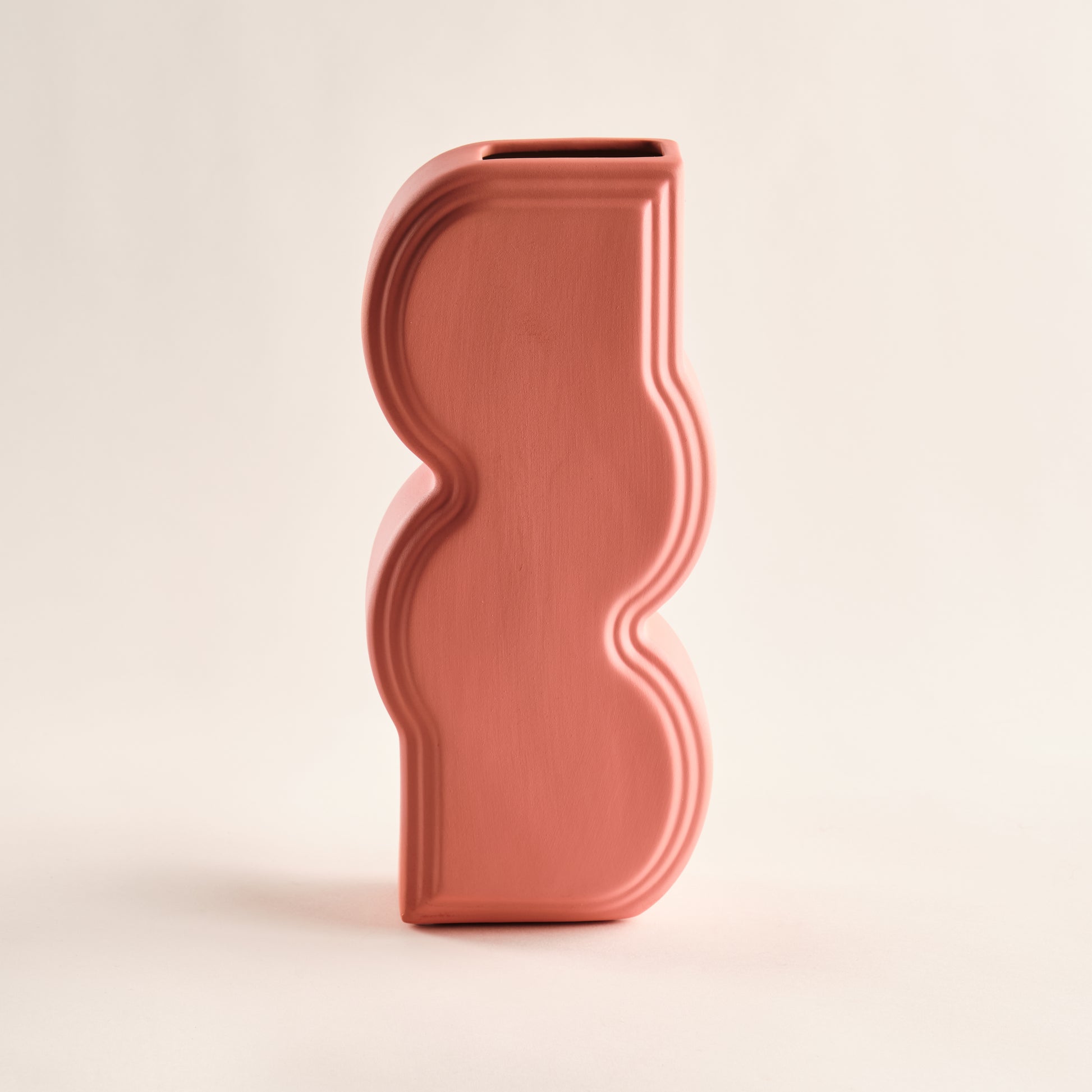 Porzellanvase "Whirl" in einem warmen Korallrosa-Ton. Die weichen, geschwungenen Linien des Designs verleihen der Vase einen eleganten und modernen Look. Ideal für minimalistische und zeitlose Dekoration.