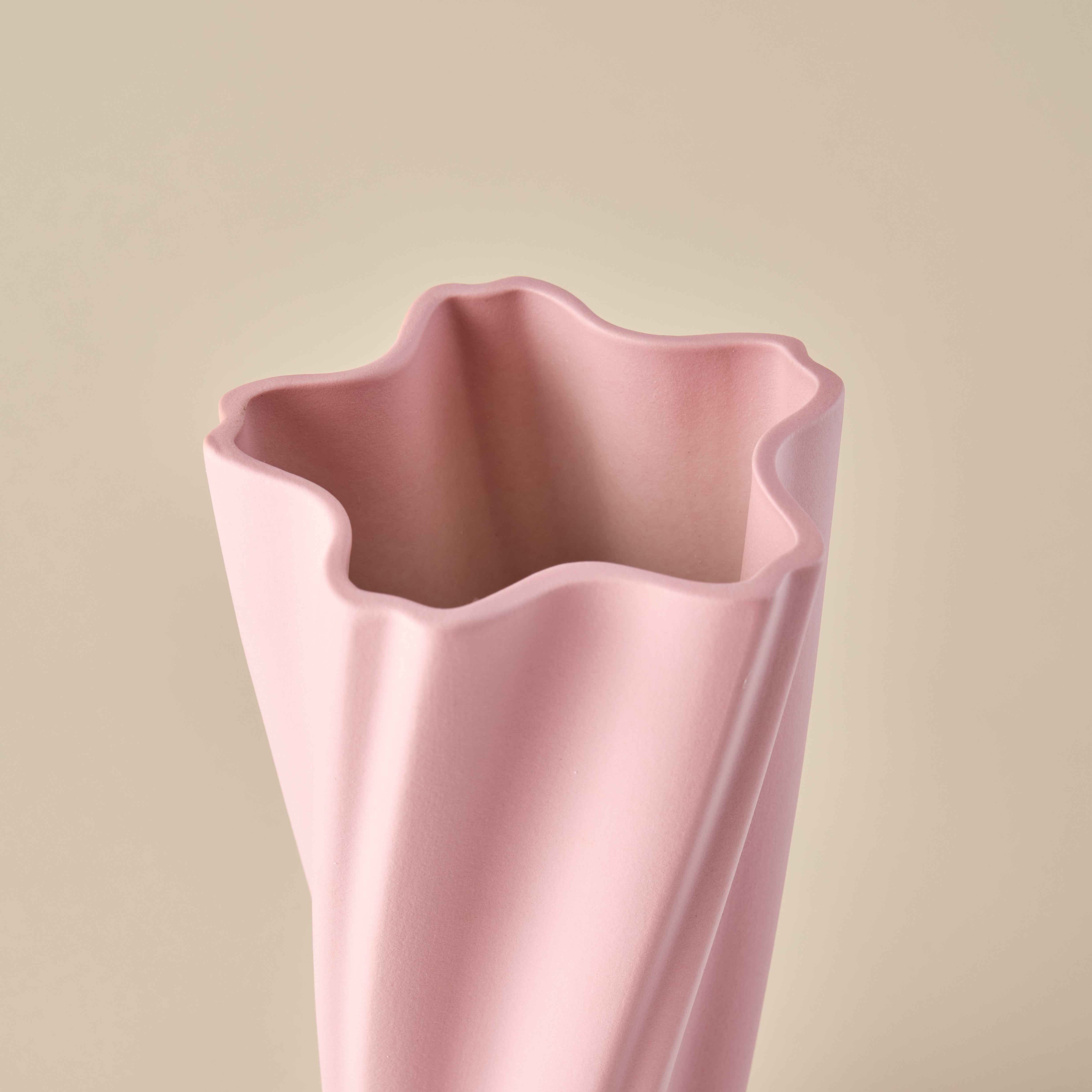 Detailaufnahme der Porzellanvase "Wind" in Rosa. Das wellenförmige Design der Öffnung unterstreicht die dynamische und moderne Gestaltung der Vase, ideal für ein zeitgemäßes Interieur oder als stilvolle Dekoration.