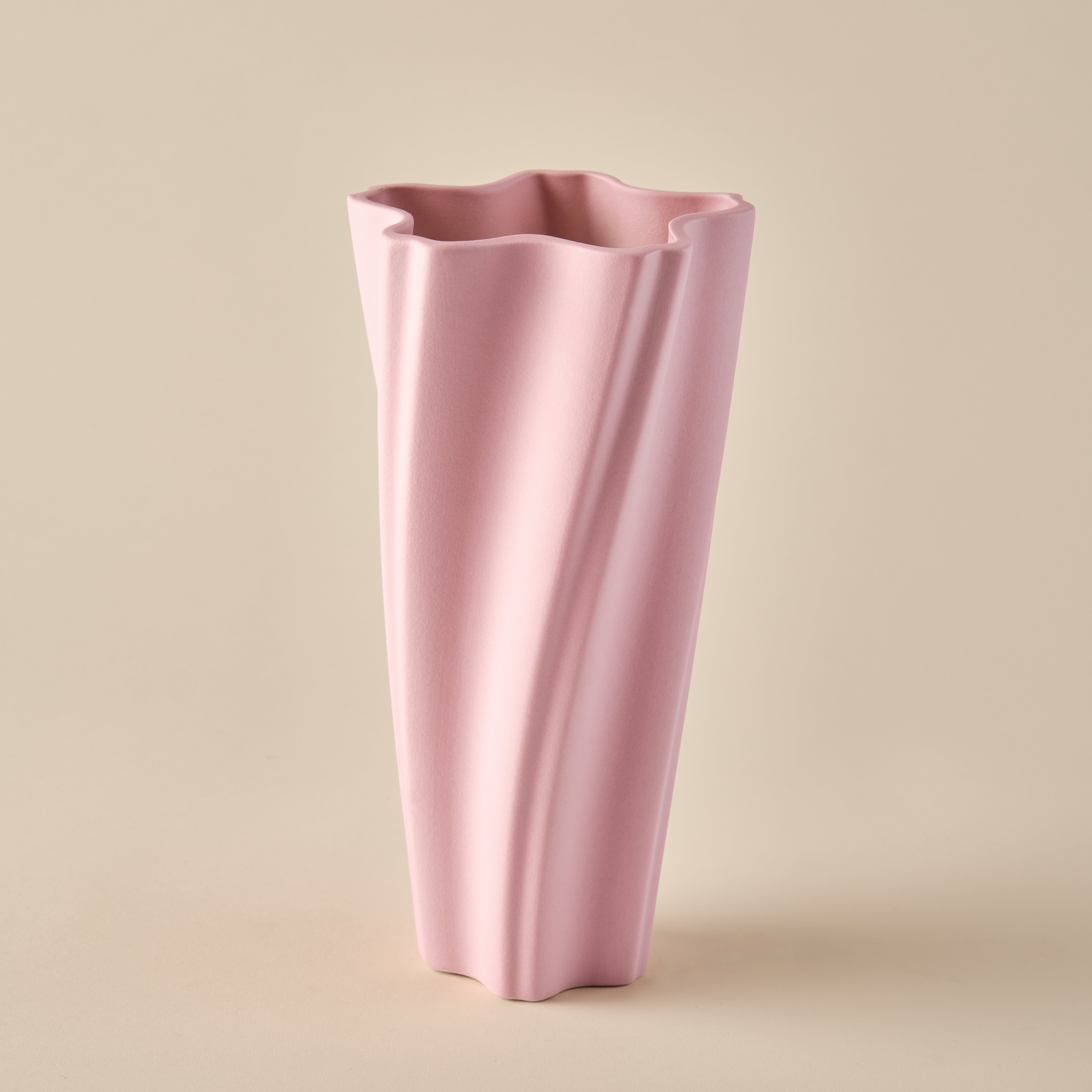 Porzellanvase "Wind" in Rosa. Die Vase besticht durch ihr elegantes, wellenförmiges Design und eine minimalistische Ästhetik. Perfekt als Dekorationsobjekt oder für stilvolle Blumenarrangements.